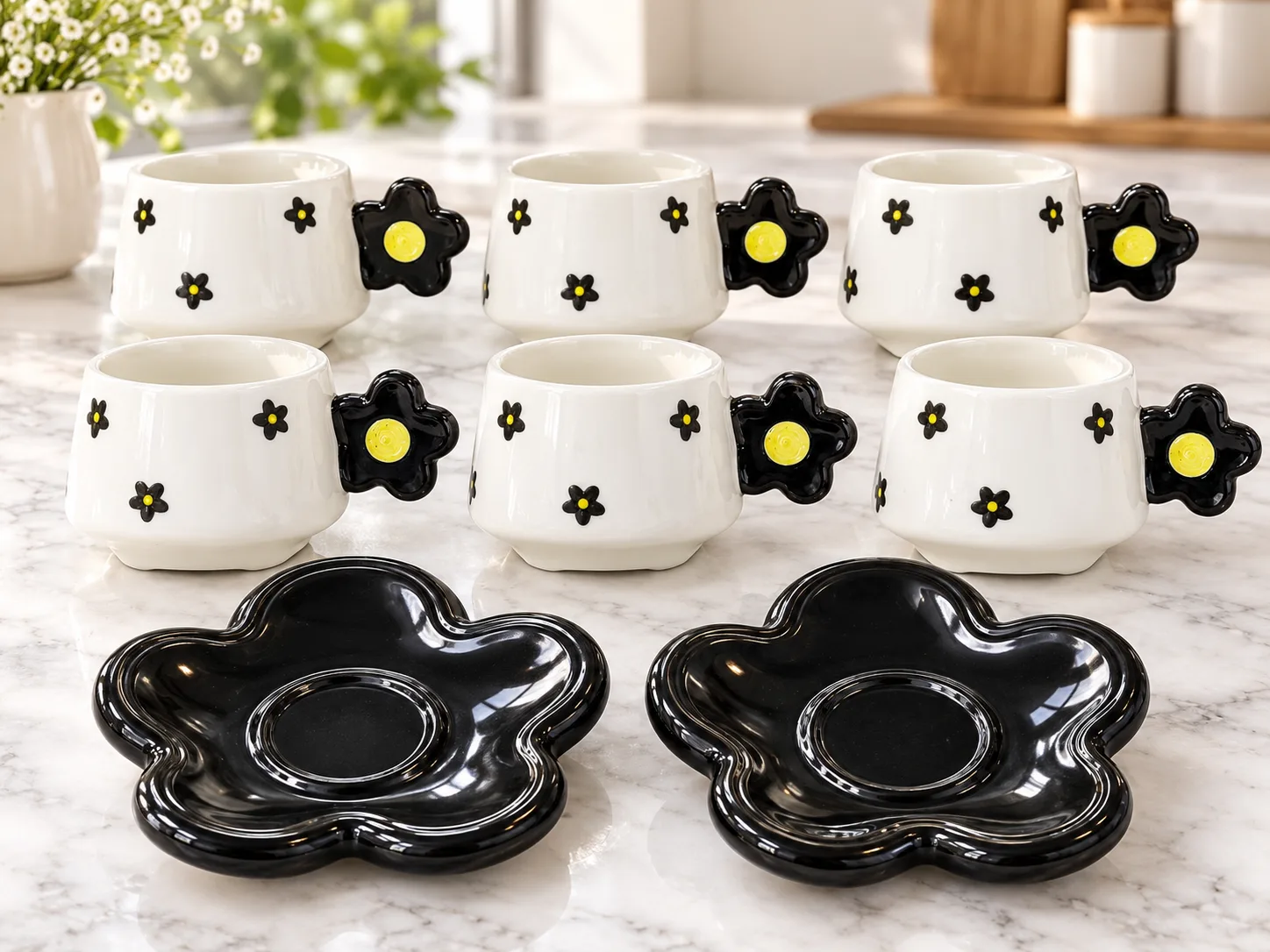 A set of black and white coffee and tea cups with a floral design